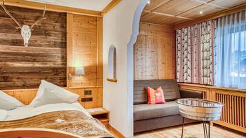 Un interior de madera con una cama, un sofá, una mesa de vidrio y un cráneo de ciervo montado en la pared.