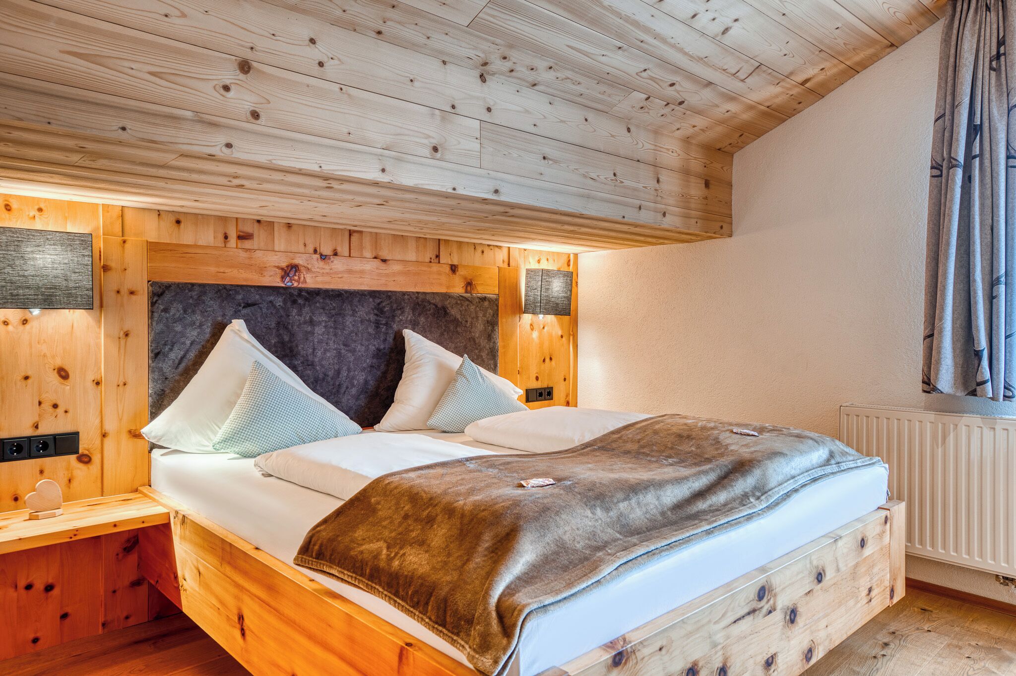 Una cama de madera con cabecera, mesitas de noche y un radiador.