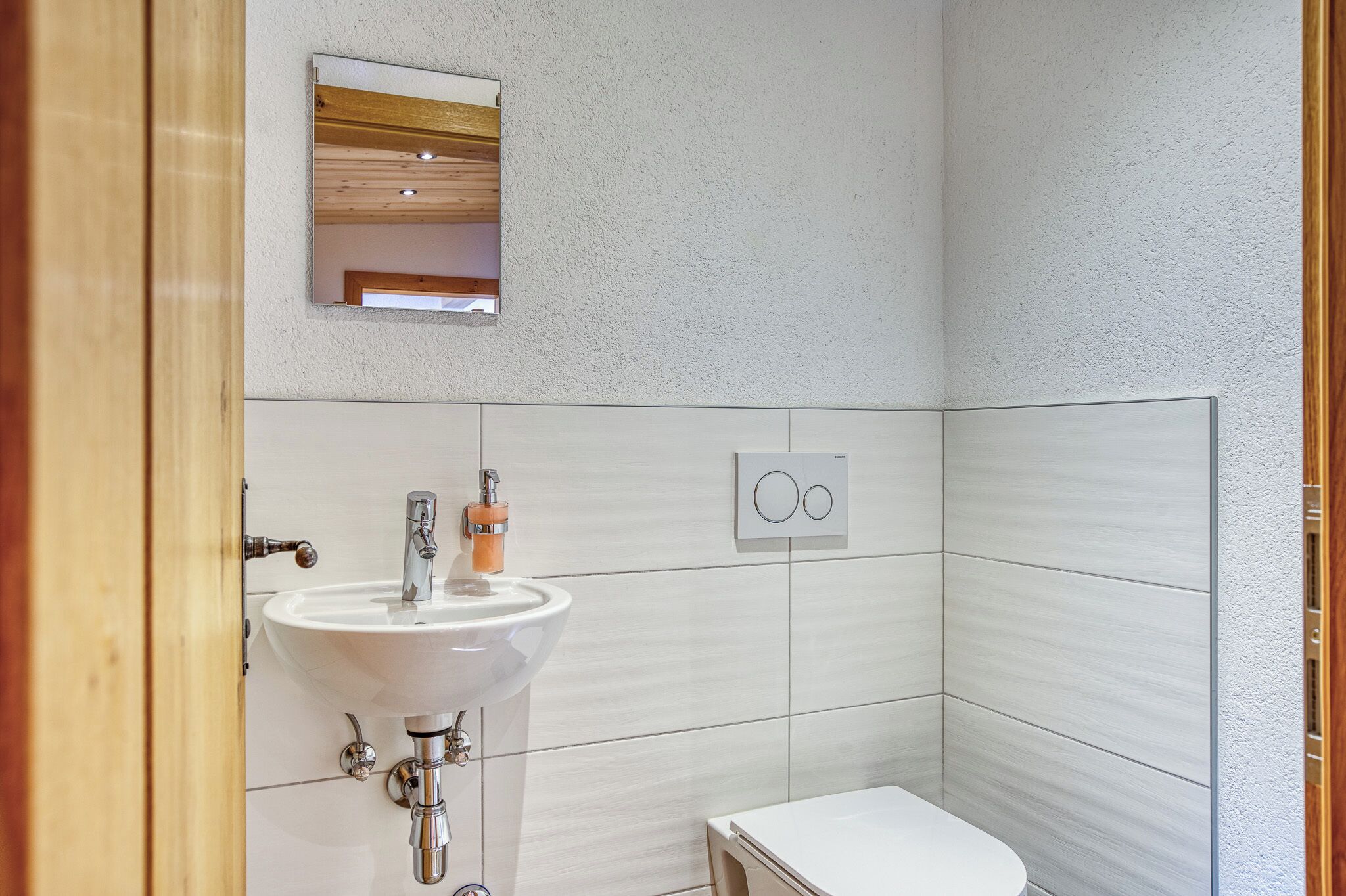 Een badkamer met een wit wastafel, een spiegel en een toilet.