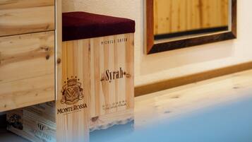 A wooden cabinet with a red cloth cover, a wooden box labeled 'Syrano,' and a framed picture on the wall.