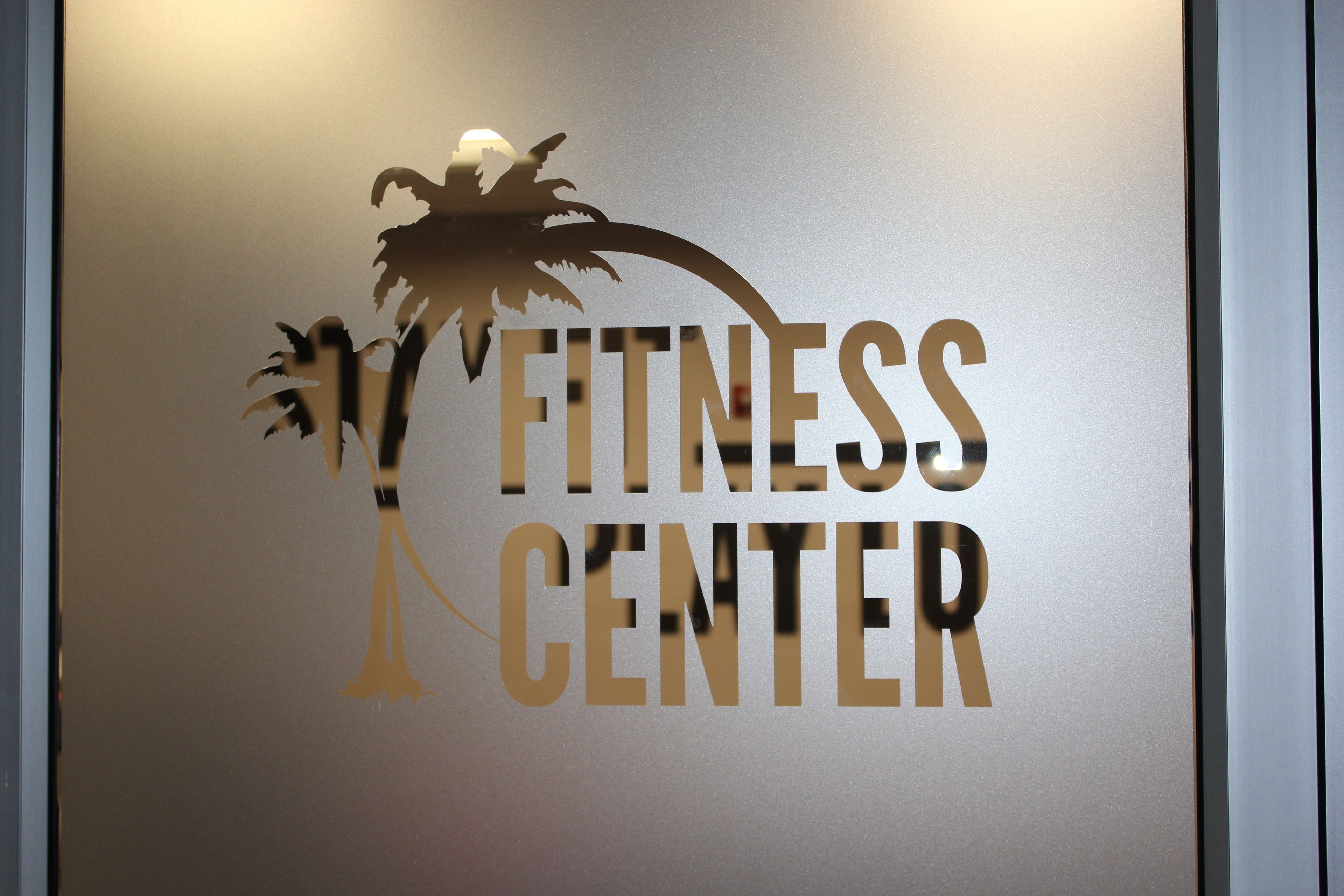 Pared con el logotipo de un gimnasio, que incluye palmeras y la inscripción 'FITNESS CENTER'.