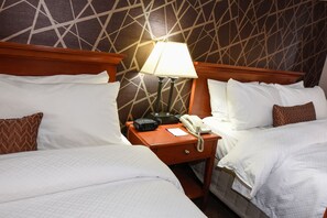 A hotel room with two beds, a nightstand with a lamp, a telephone, and a clock. - Wheeling Island Hotel-Casino-Racetrack (Wheeling)