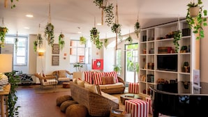 A living room with wicker furniture, a television, and hanging plants. - WOT Sarrazola Soul (Sintra)