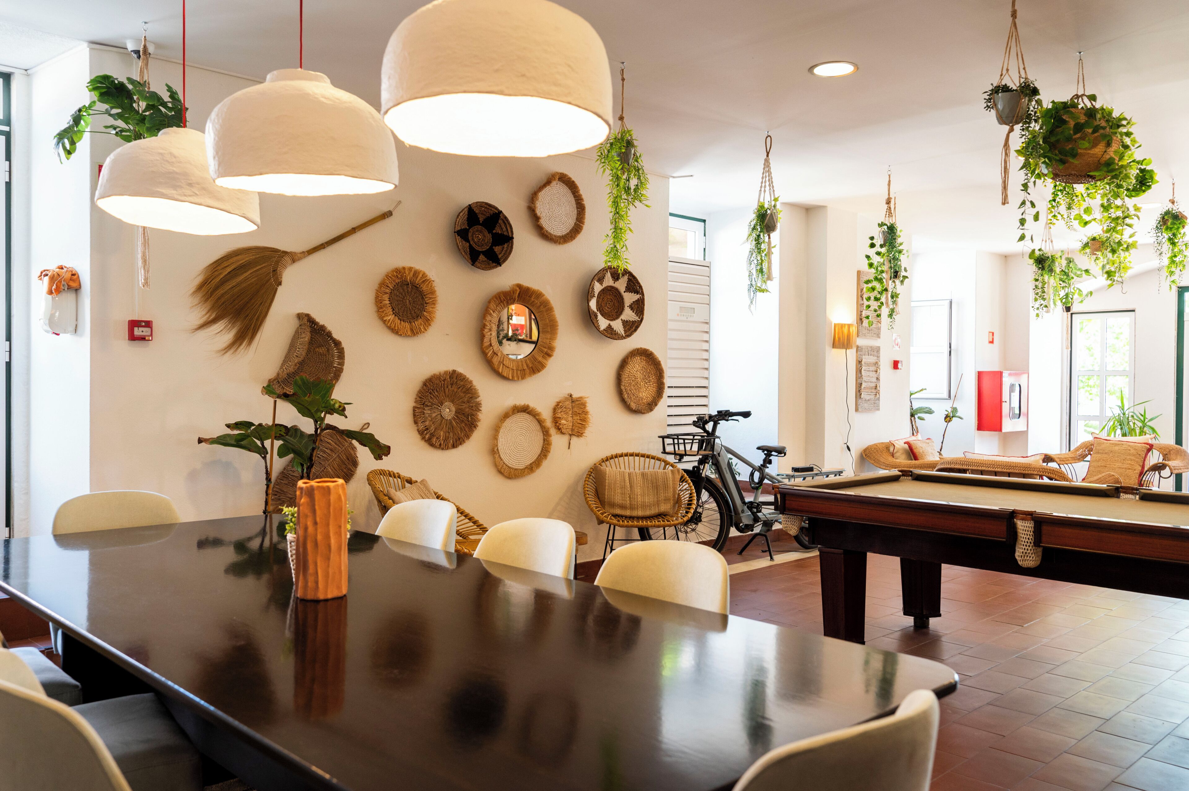 Un comedor con mesa de billar, plantas colgantes y una bicicleta.