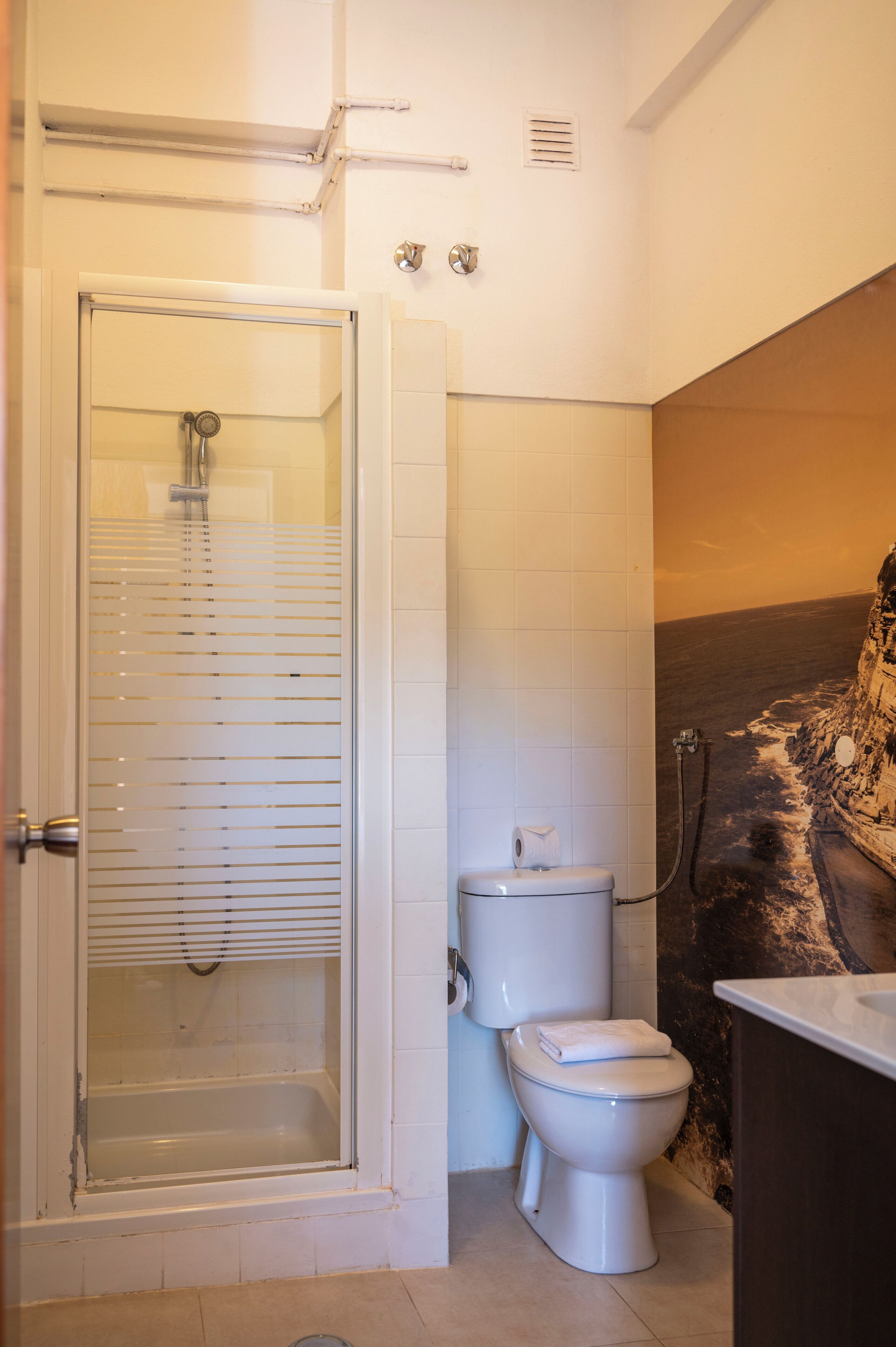 A bathroom with a glass-enclosed shower, a toilet, and a sink.