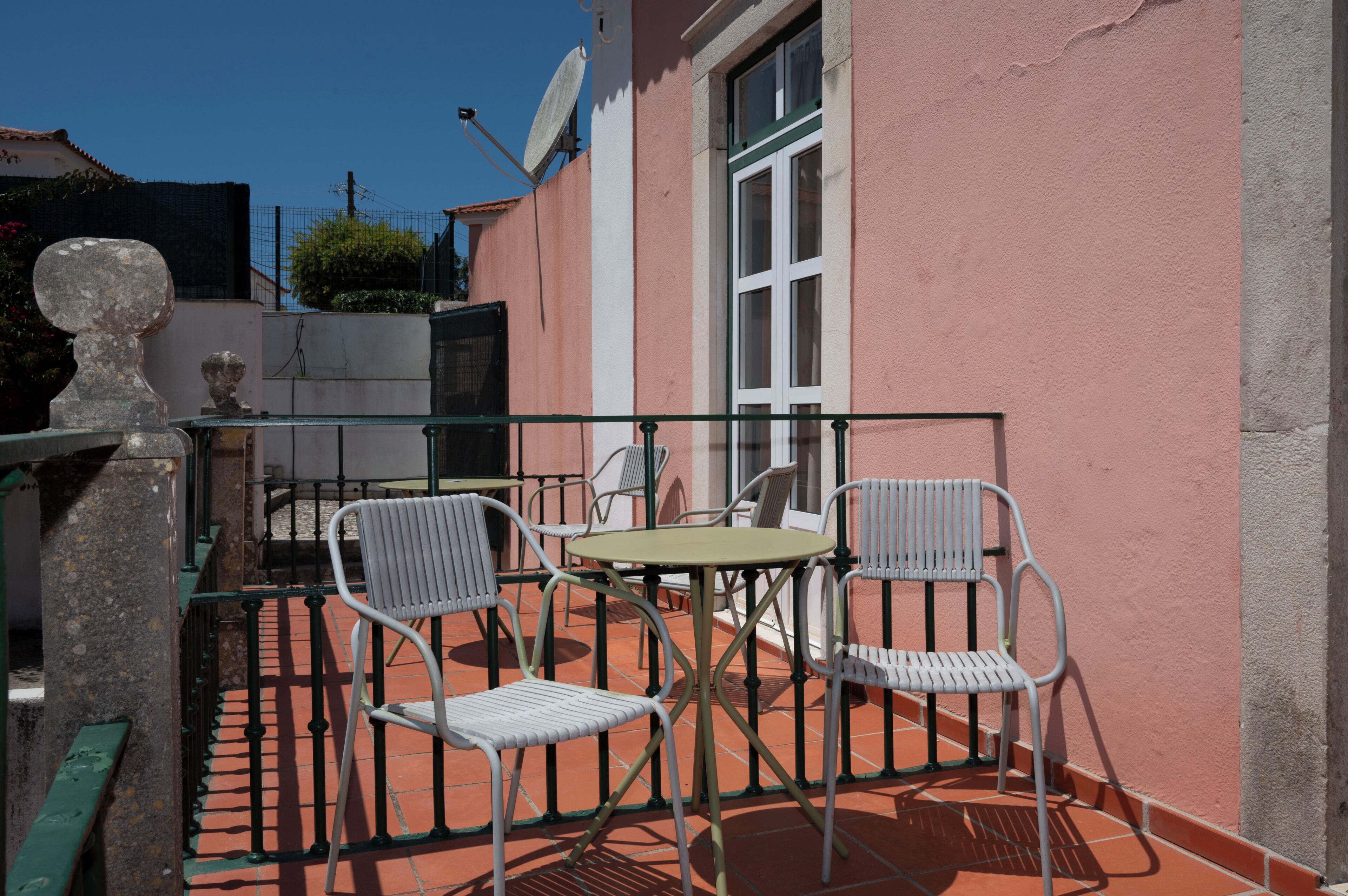 A patio with a table and two chairs, a satellite dish, and a stone sculpture.