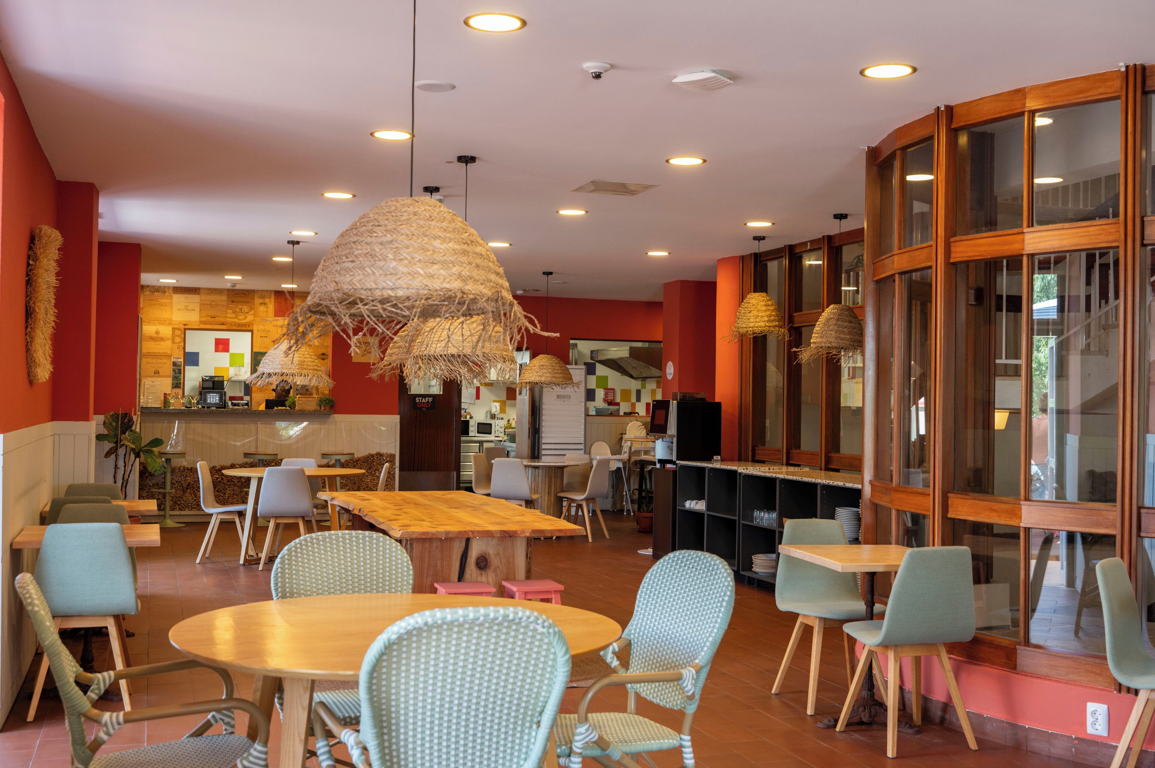 A restaurant with round tables, chairs, and hanging light fixtures.