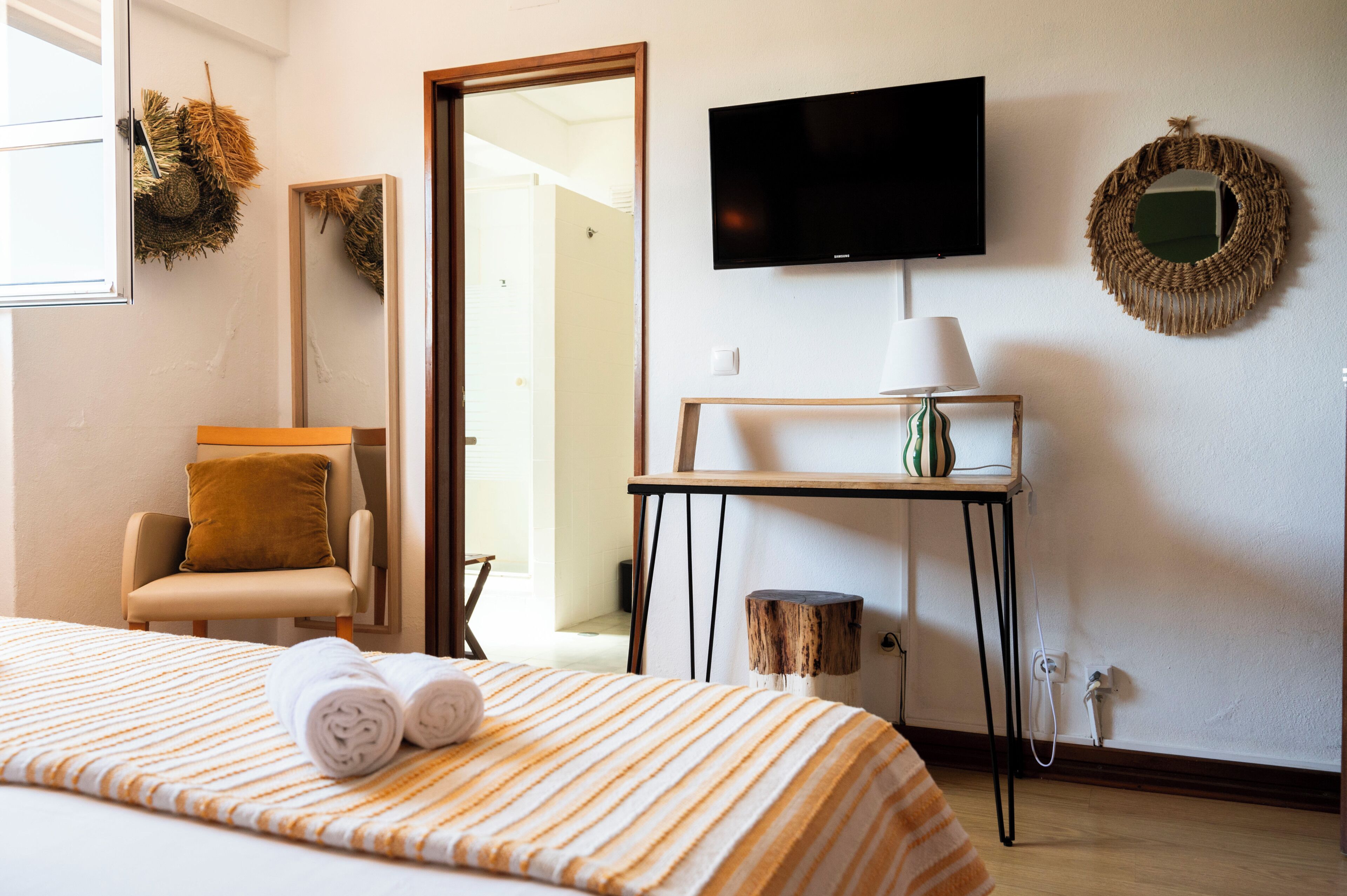 Une chambre d’hôtel avec un lit, une chaise, une télévision, une lampe et une petite table.