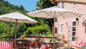 A deck with outdoor furniture, including chairs and a sofa, under striped umbrellas. - WOT Sarrazola Soul (Sintra)