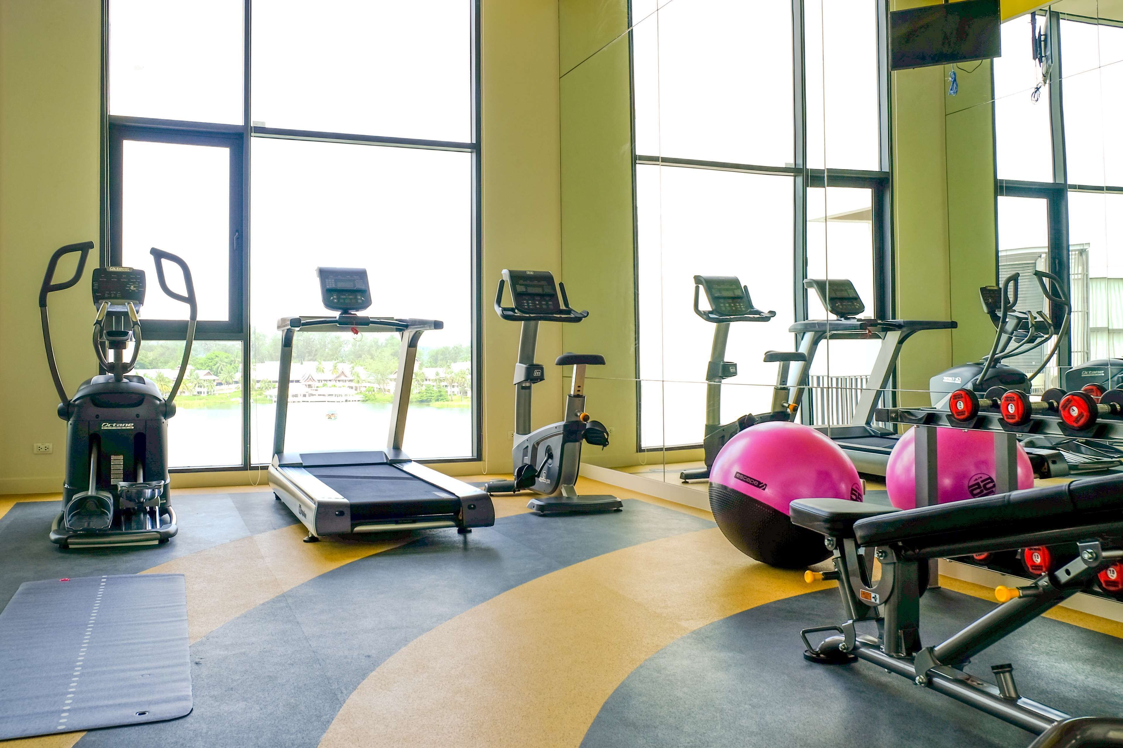 Una palestra dotata di diverse attrezzature per l'allenamento, tra cui tapis roulant, cyclette e macchinari per pesi.
