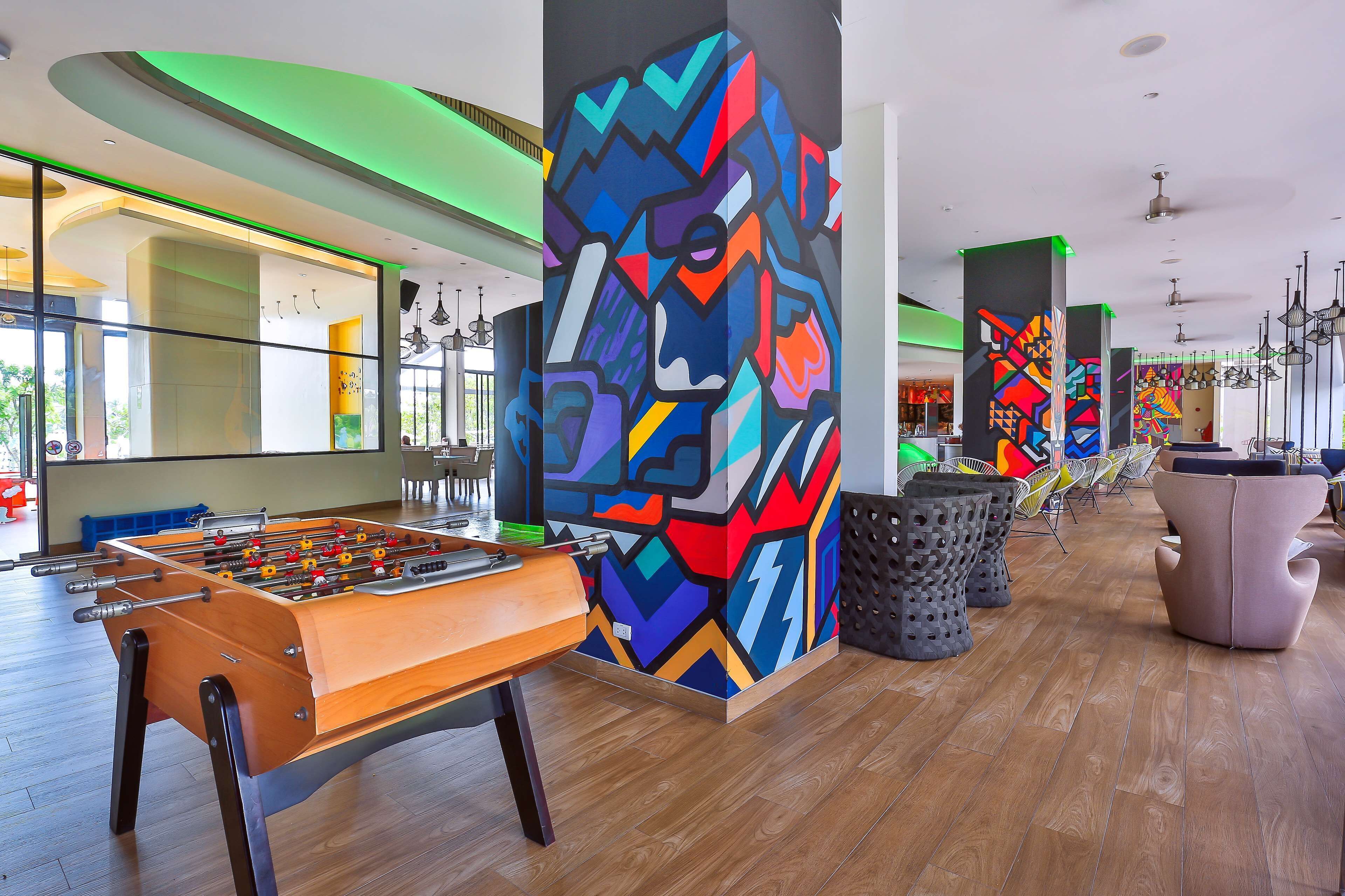 A modern interior with a foosball table, colorful abstract art, and contemporary furniture.