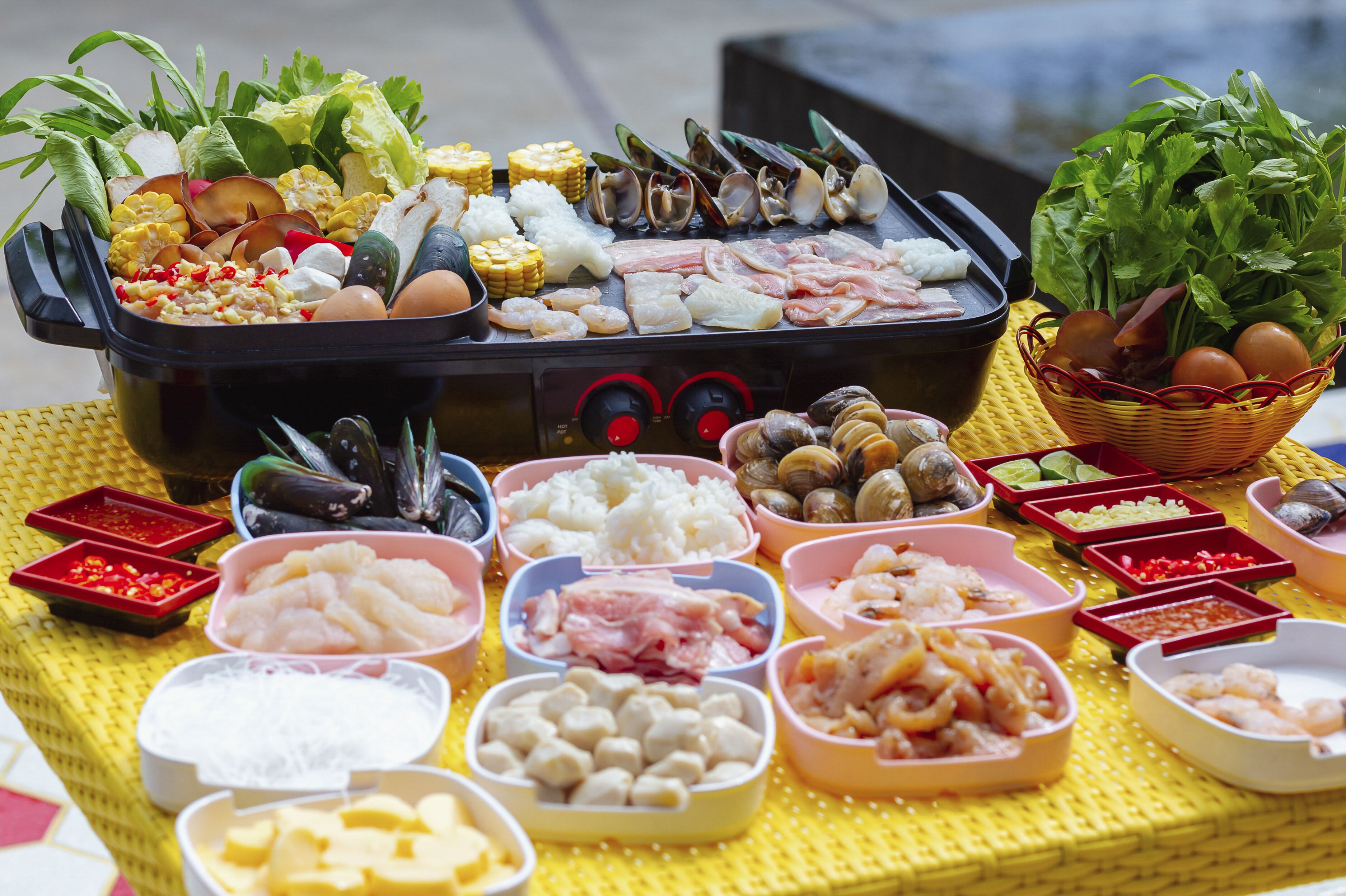 Fisk og grøntsager i forskellige varianter anrettet på et bord med en grill i midten.