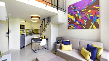 Una sala moderna con sofá, reposapiés y un cuadro abstracto llamativo.