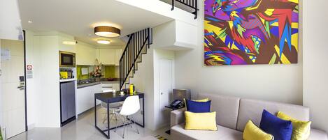A modern living room with a sofa, ottoman, and a vibrant abstract painting.