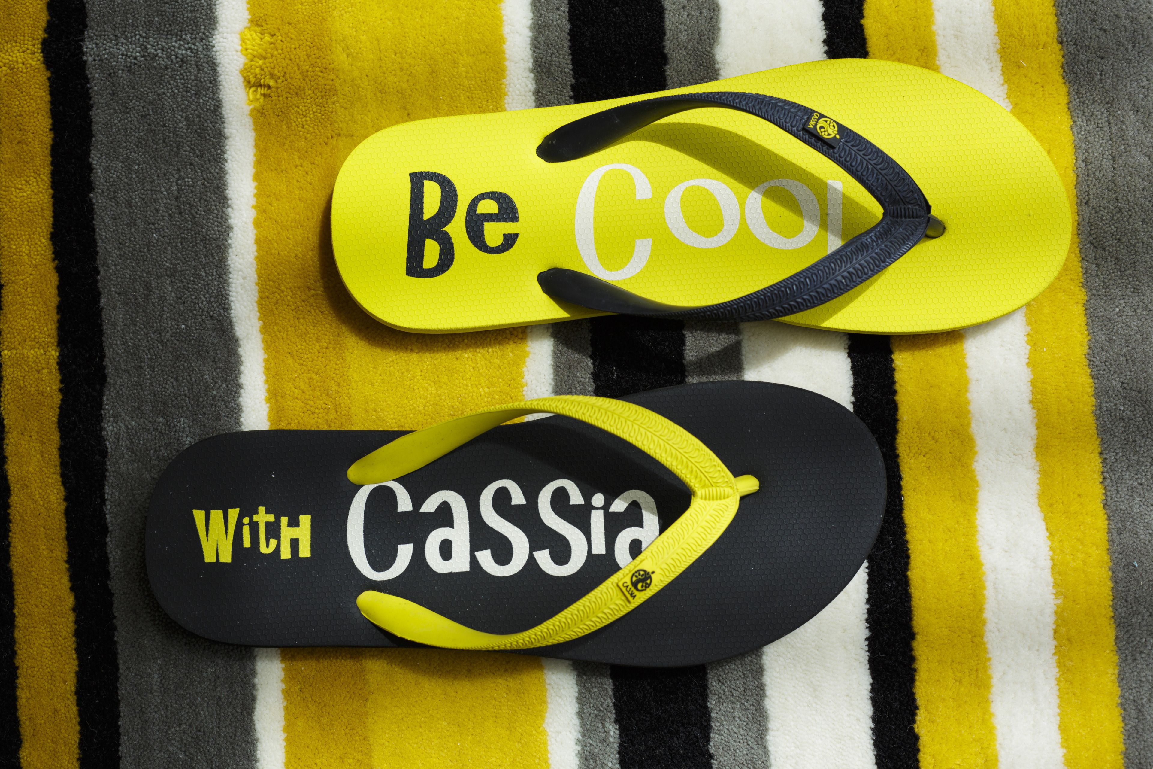 Two flip-flops with text on them, placed on a striped fabric.