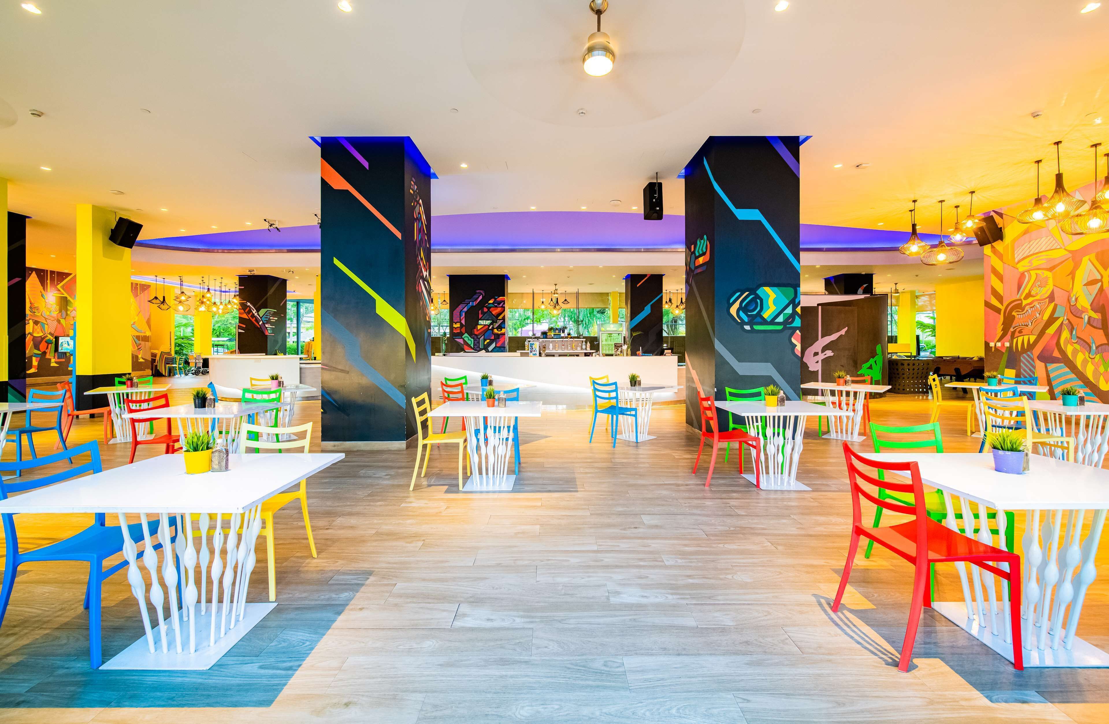 A spacious indoor area with multiple tables and chairs, a reception desk, and colorful wall art.