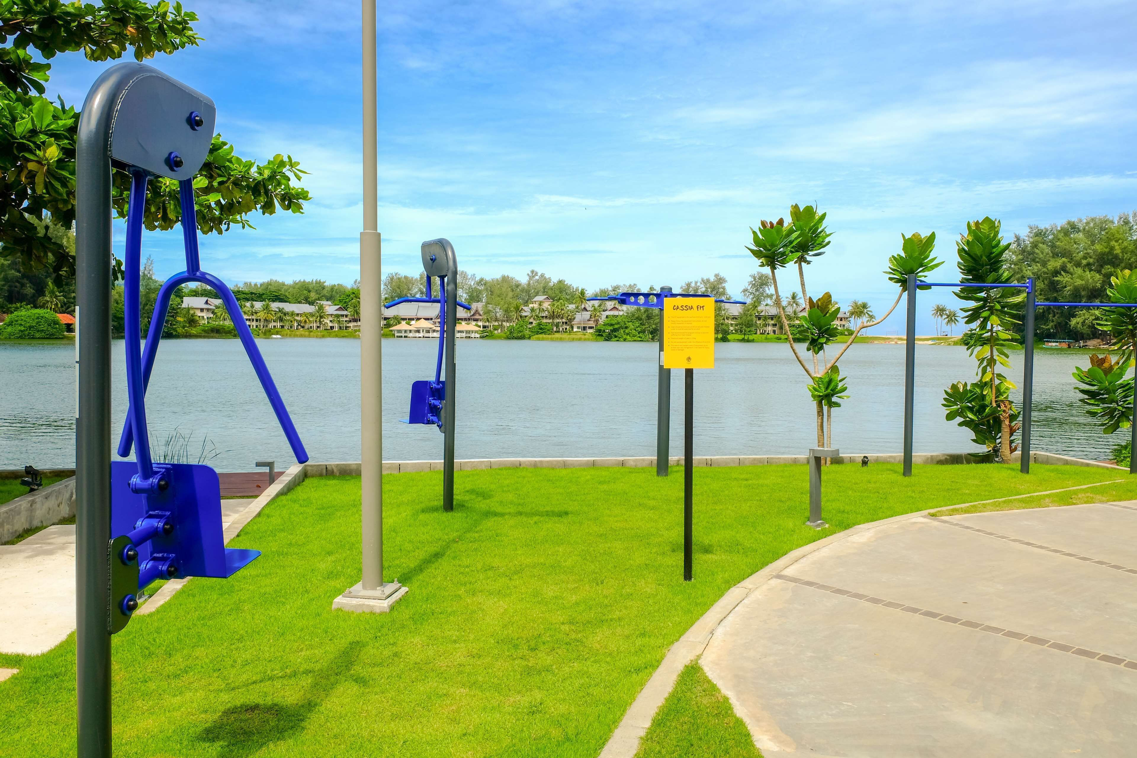 Un parque con equipo de ejercicio, un cartel y vistas a un cuerpo de agua.