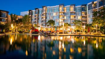 A modern hotel with a pool, multiple balconies, and outdoor seating areas.