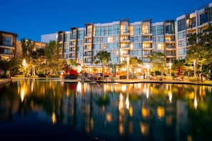 Un hotel moderno con piscina, varios balcones y zonas de estar al aire libre.