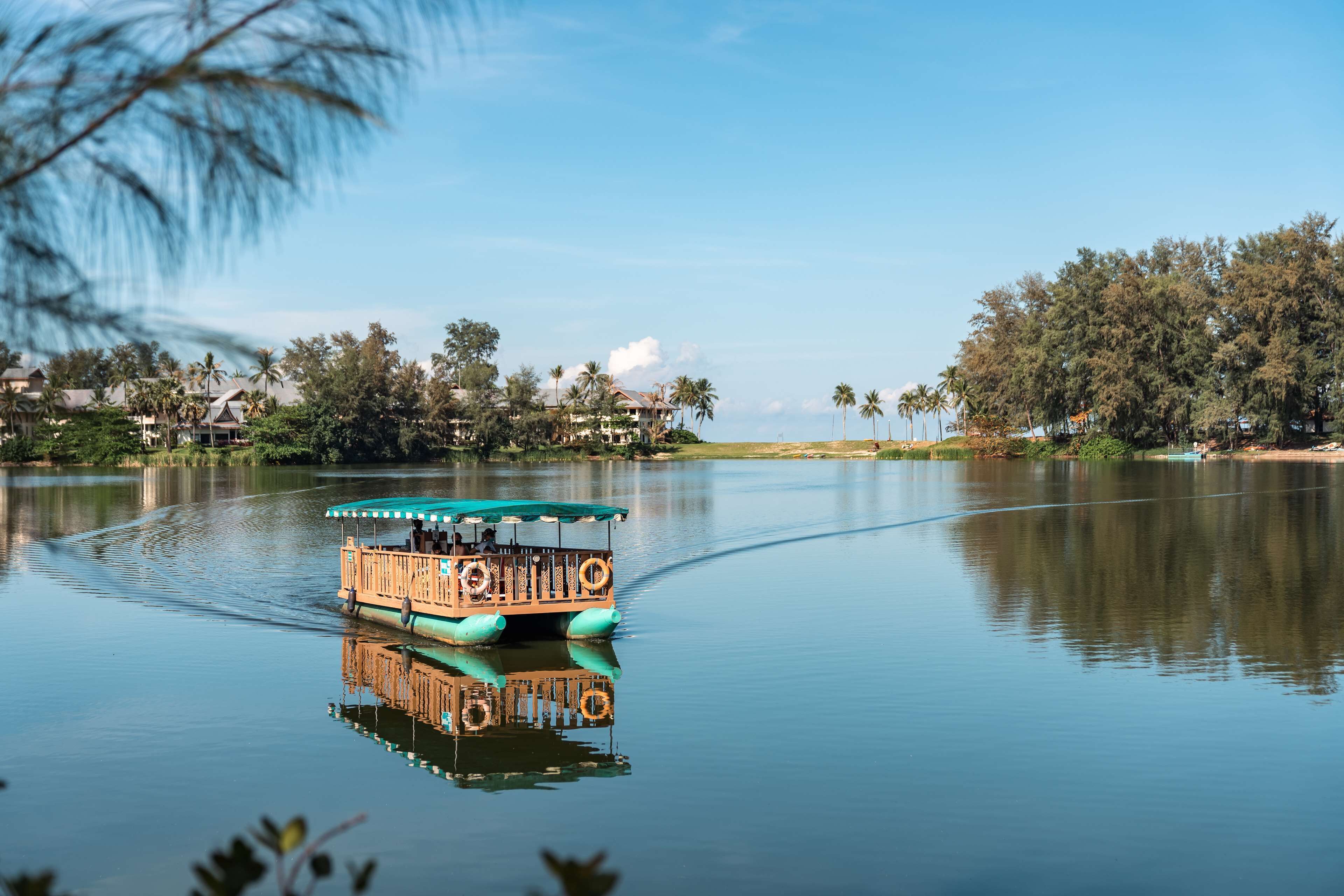 A boat on a calm river with a reflection of the surrounding landscape.