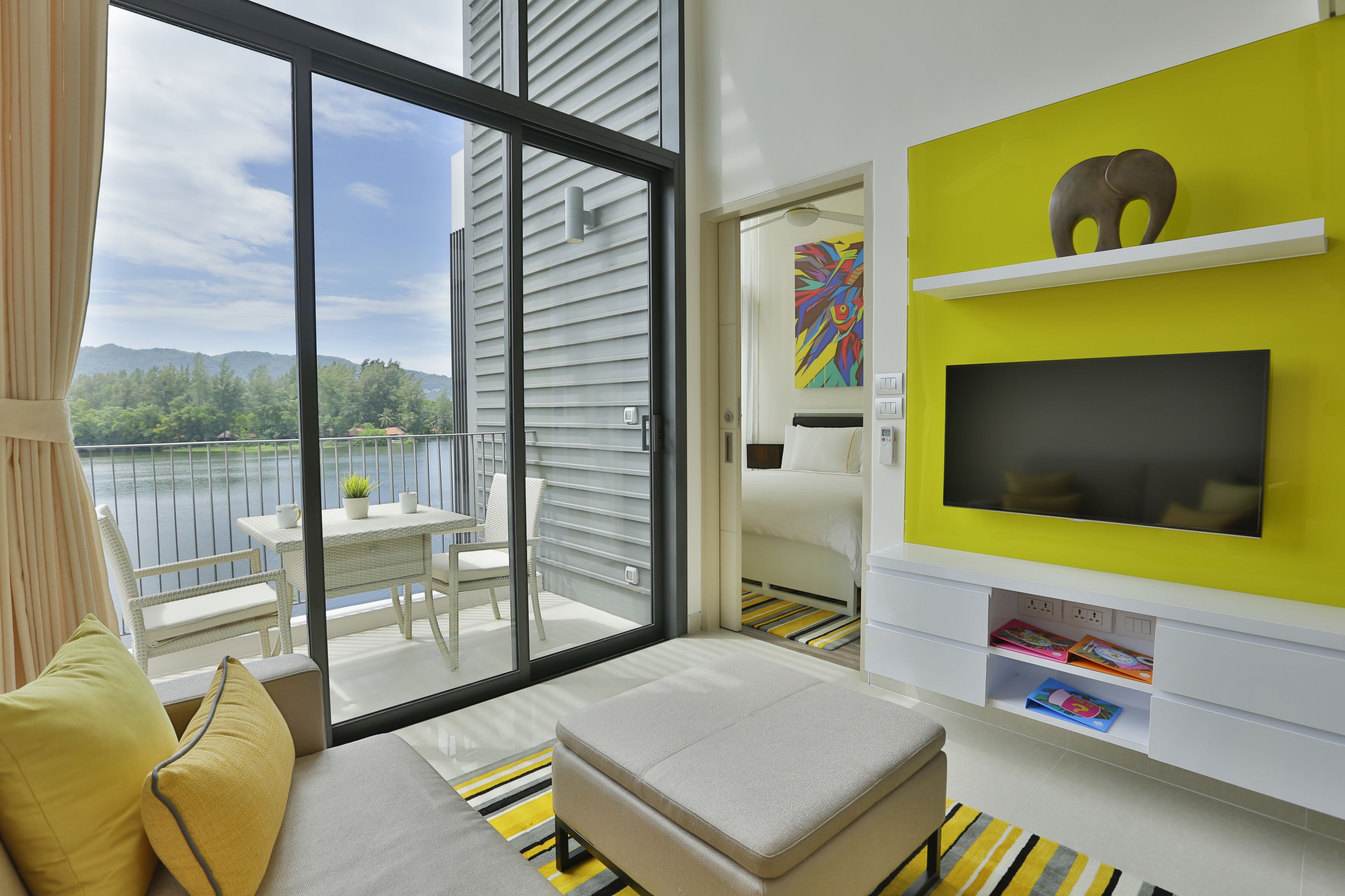 Een moderne kamer met een balkon, een televisie en een boekenkast.