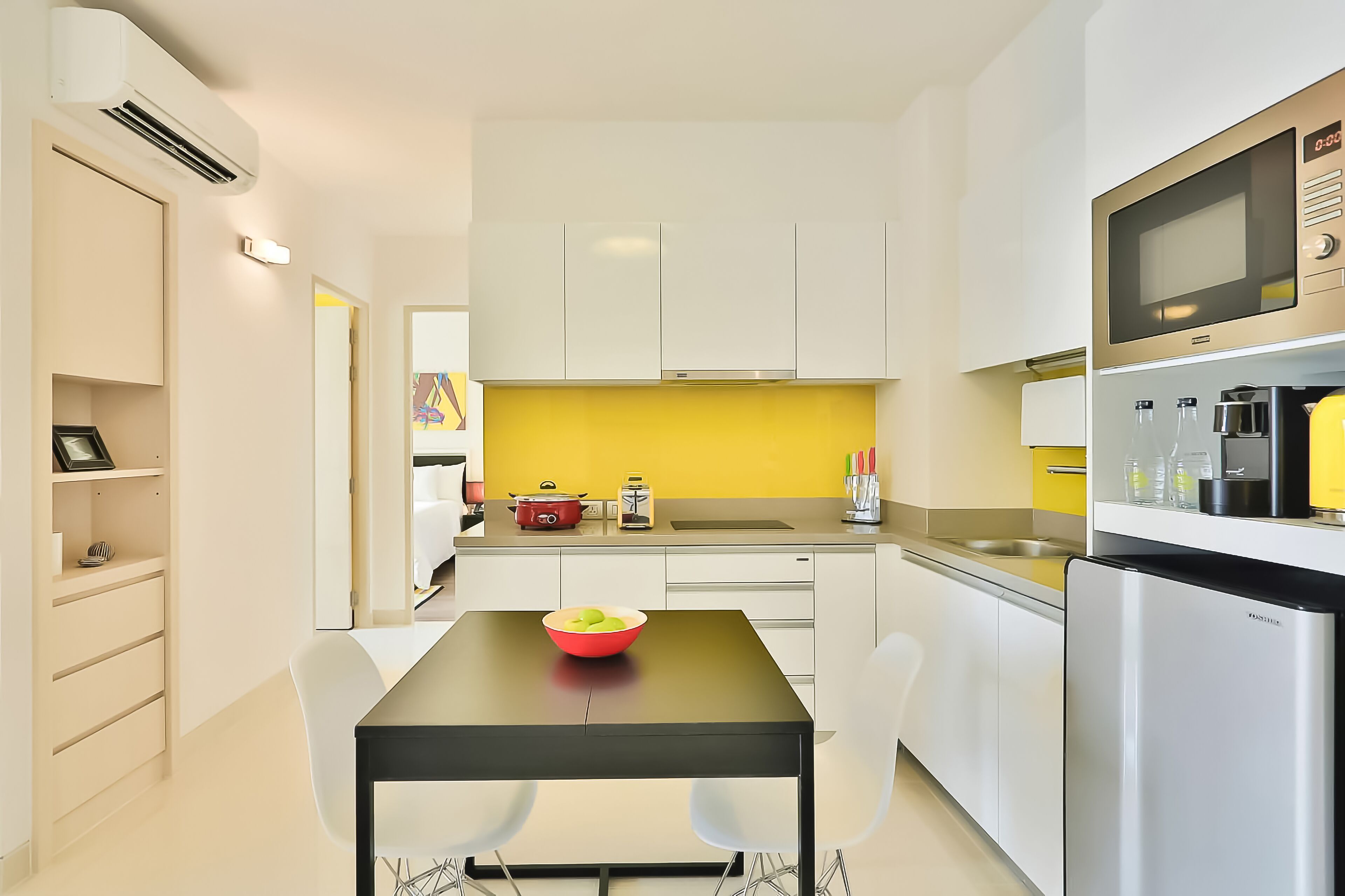 A modern kitchen with white cabinets, a yellow backsplash, and a black dining table.