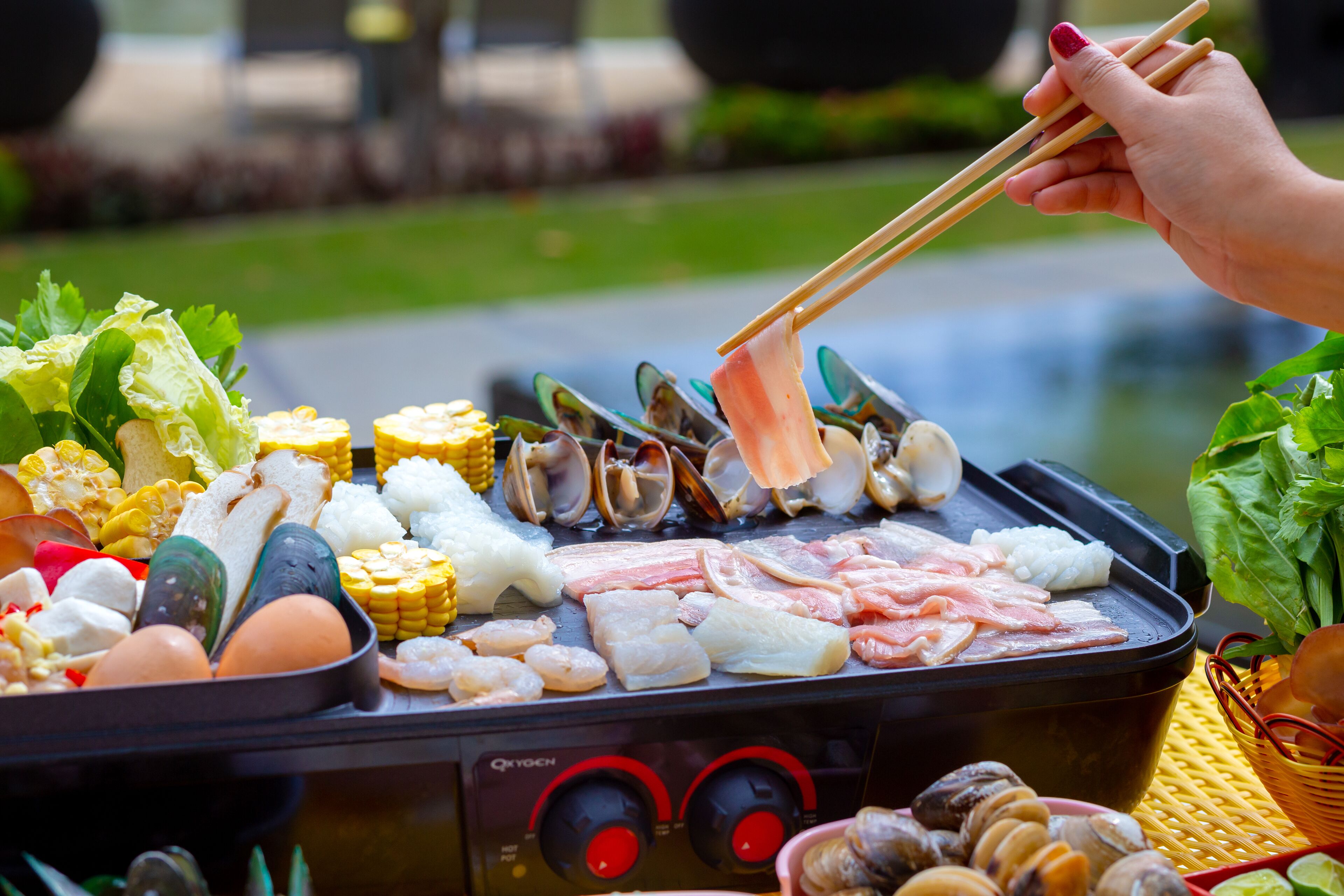 A portable grill with various seafood and vegetables.