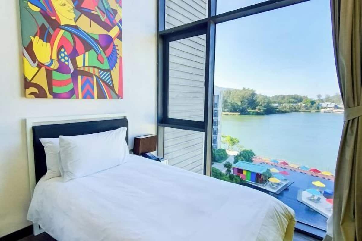 A hotel room with a bed, a large window, and a view of a lake.