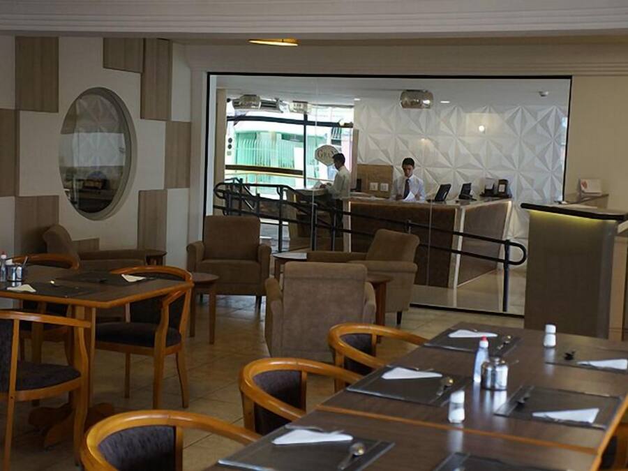 A hotel lobby with a reception desk, seating area, and a large window.