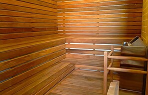 Un sauna avec des parois en lambris de bois et un banc en métal.