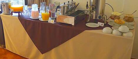 A breakfast buffet setup with various food items and beverages.