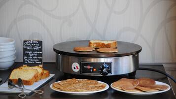 A breakfast setup with a griddle, pancakes, and toast.