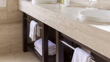 A modern bathroom with two sinks, a large mirror, and a towel rack.