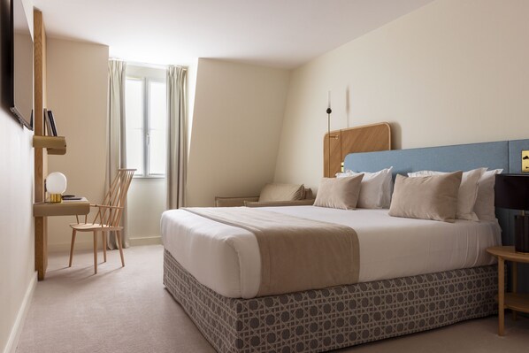 Un dormitorio con una cama grande, un escritorio, una silla y una ventana con cortinas.