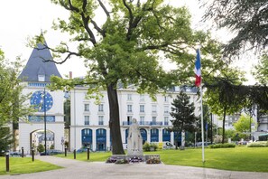 Un edificio grande con una torre de reloj, una estatua y una bandera.