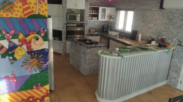 A kitchen with a central island, built-in oven, microwave, and a window. - Genesis Apartments (Noord)