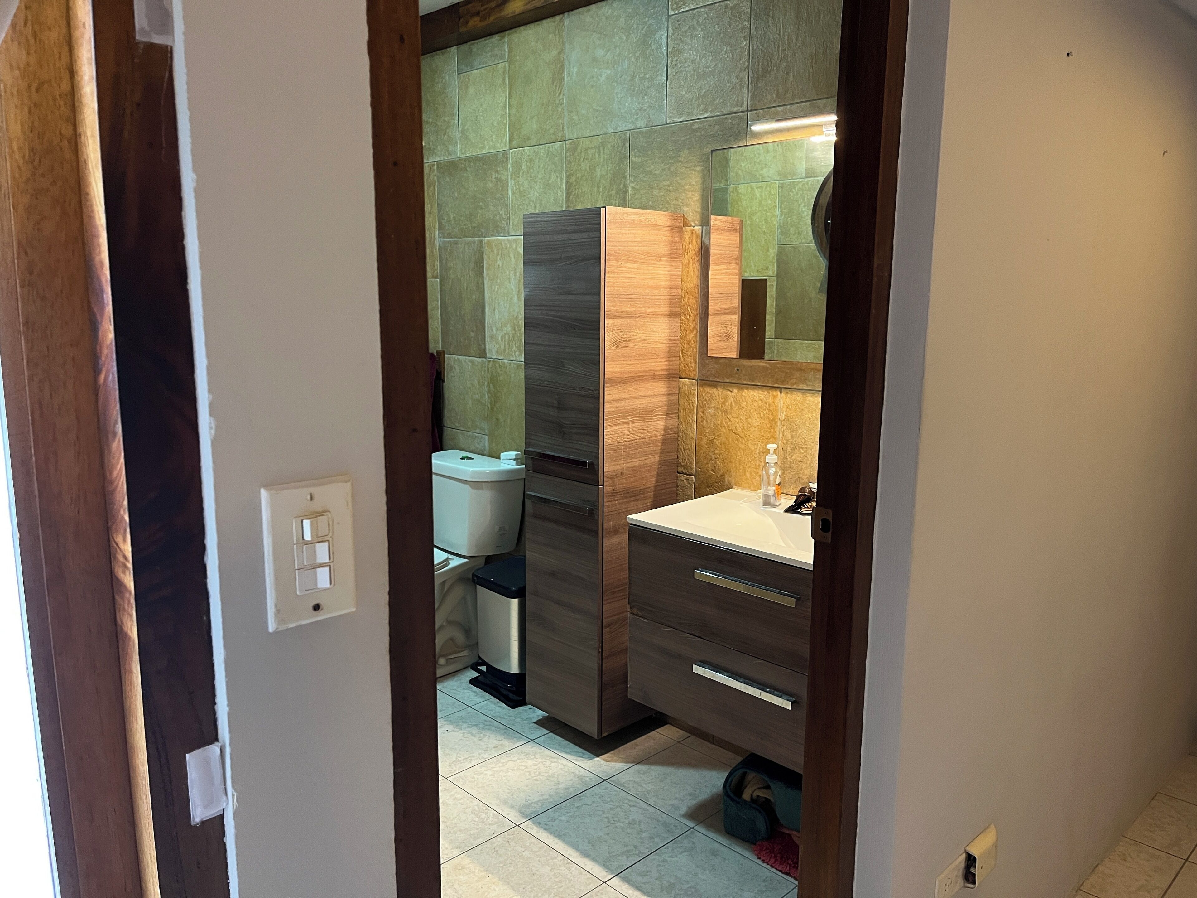 Une salle de bain équipée de toilettes, d’un lavabo et d’un meuble en bois.