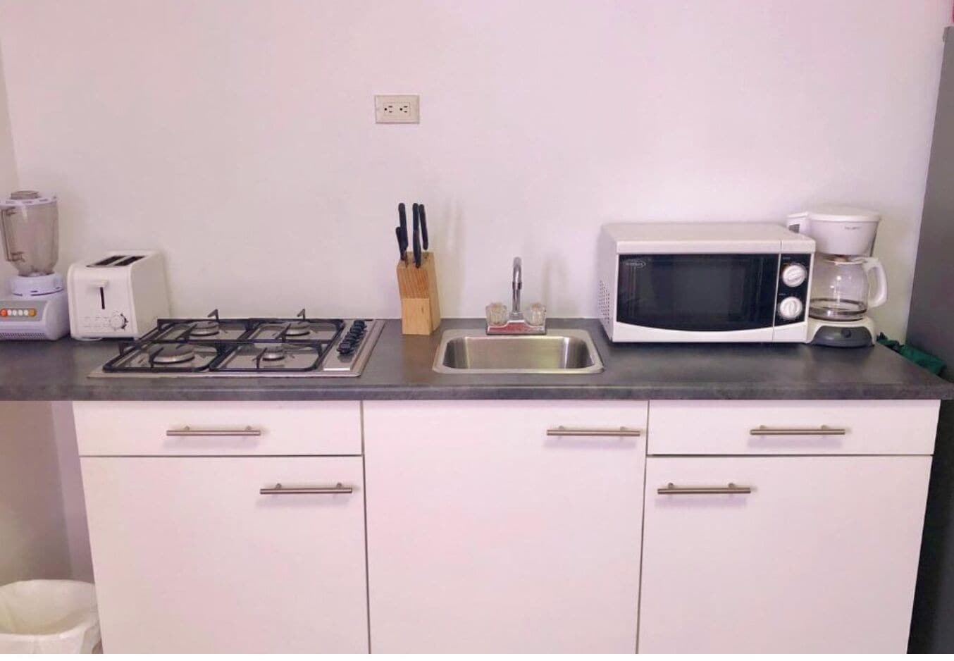 Una kitchenette equipada con estufa a gas, microondas, tostadora, cafetera y pileta.