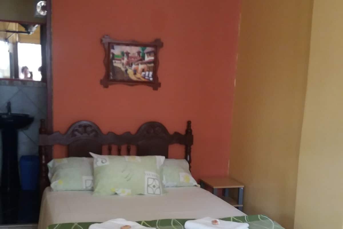 A bed with a green bedspread, a wooden headboard, and a small bedside table.