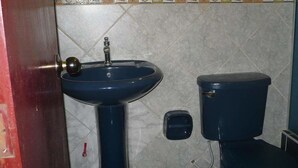 A bathroom with a blue sink, a toilet, and a small trash bin. - Nasca Trails B&B (Nazca)