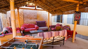 A cozy room with a foosball table, comfortable seating, and a bamboo ceiling. - Nasca Trails B&B (Nazca)