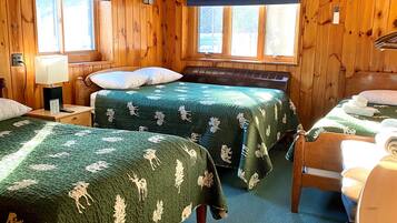 Una habitación tipo cabaña con dos camas, paredes de madera y ventanas amplias.
