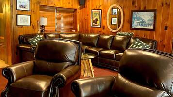 A cozy living room with leather sofas and a wooden wall.