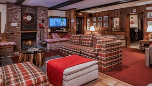 Una sala de estar acogedora con chimenea, muebles a cuadros y un televisor.