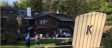 A wooden deck with Adirondack chairs and a red Adirondack chair.