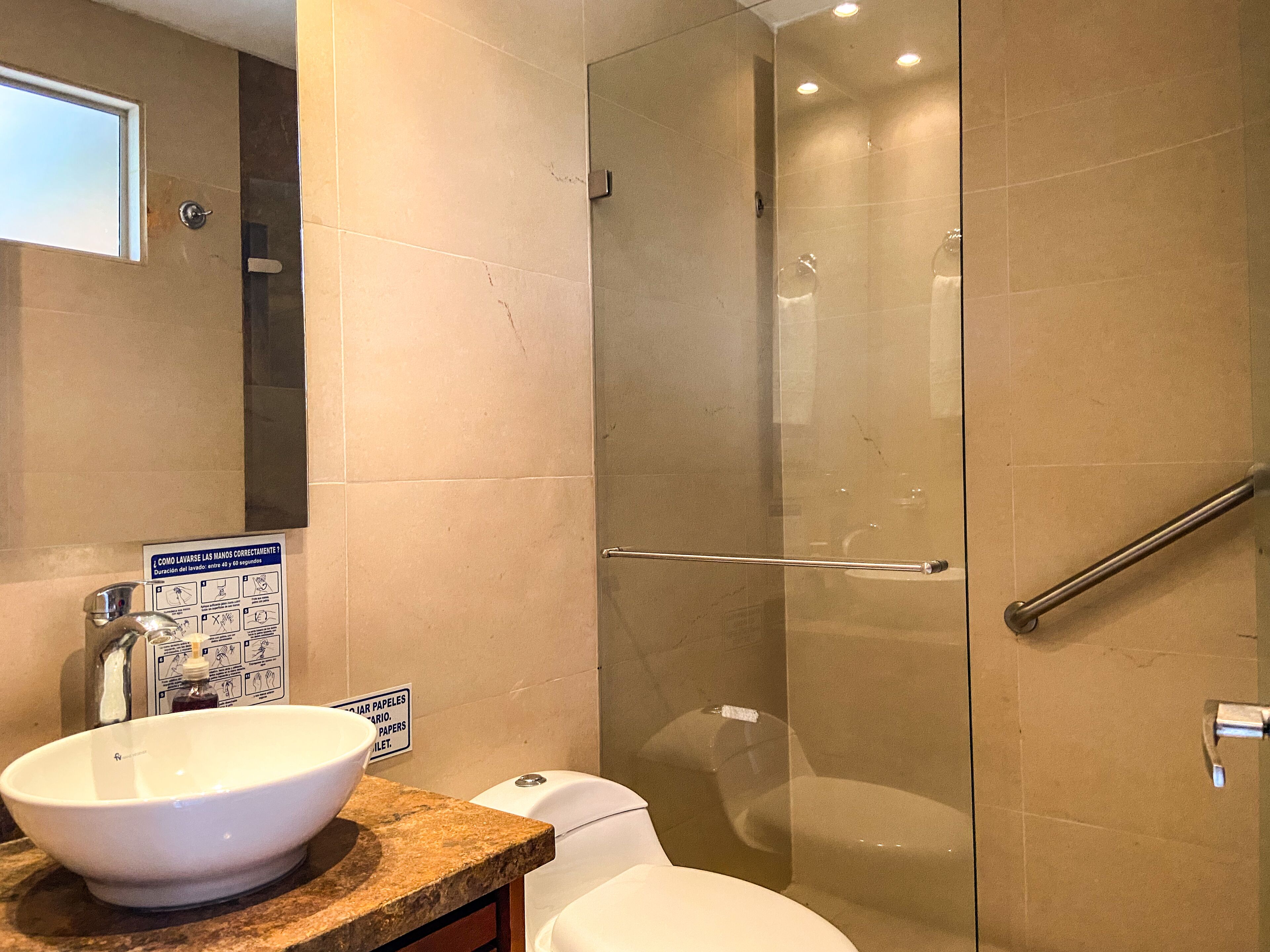 Une salle de bain avec une douche à parois de verre, un lavabo blanc et des toilettes.