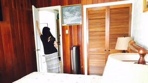 Une chambre à coucher avec un lit, une armoire en bois, une porte et une lampe fixée au mur.