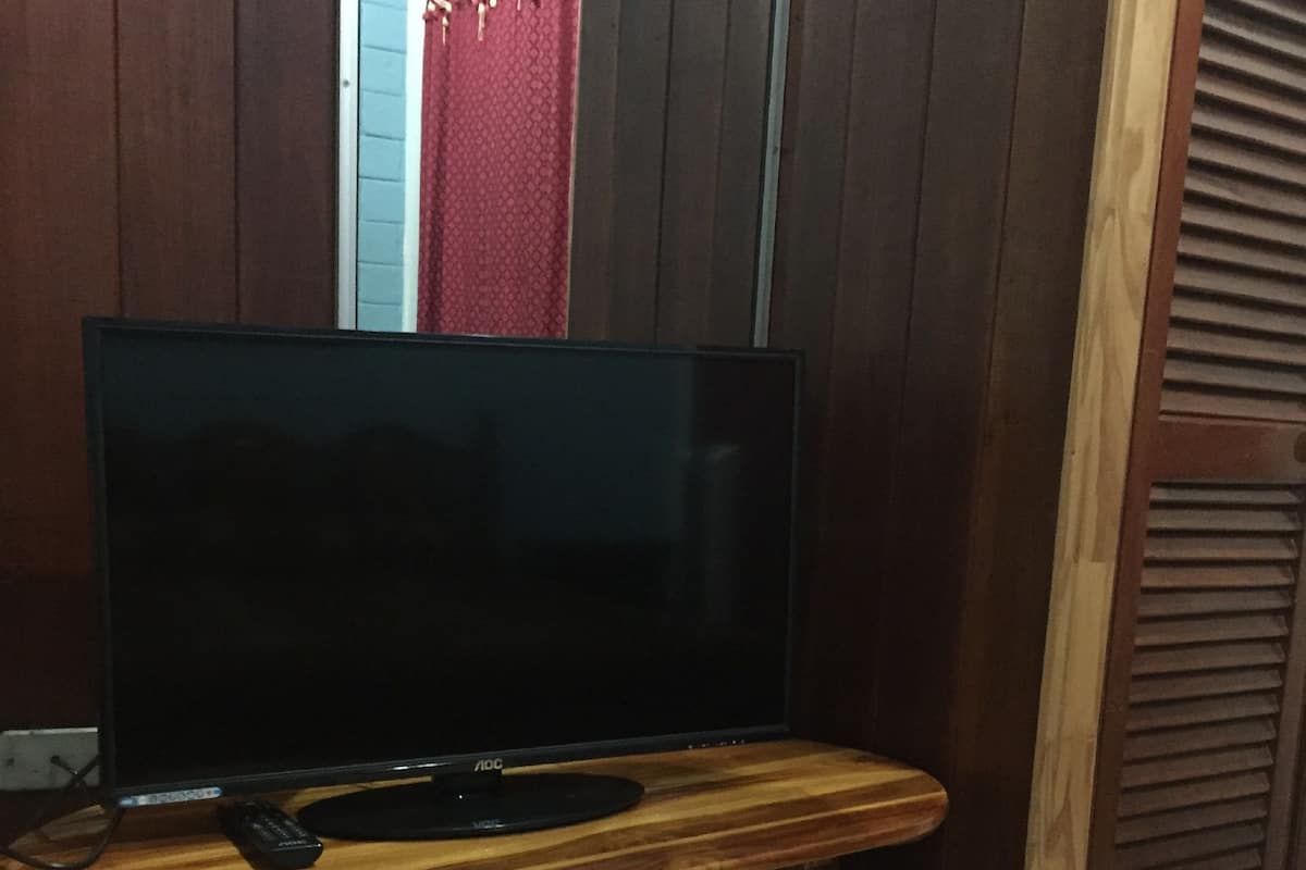 Un téléviseur posé sur un meuble en bois, avec une télécommande à proximité.