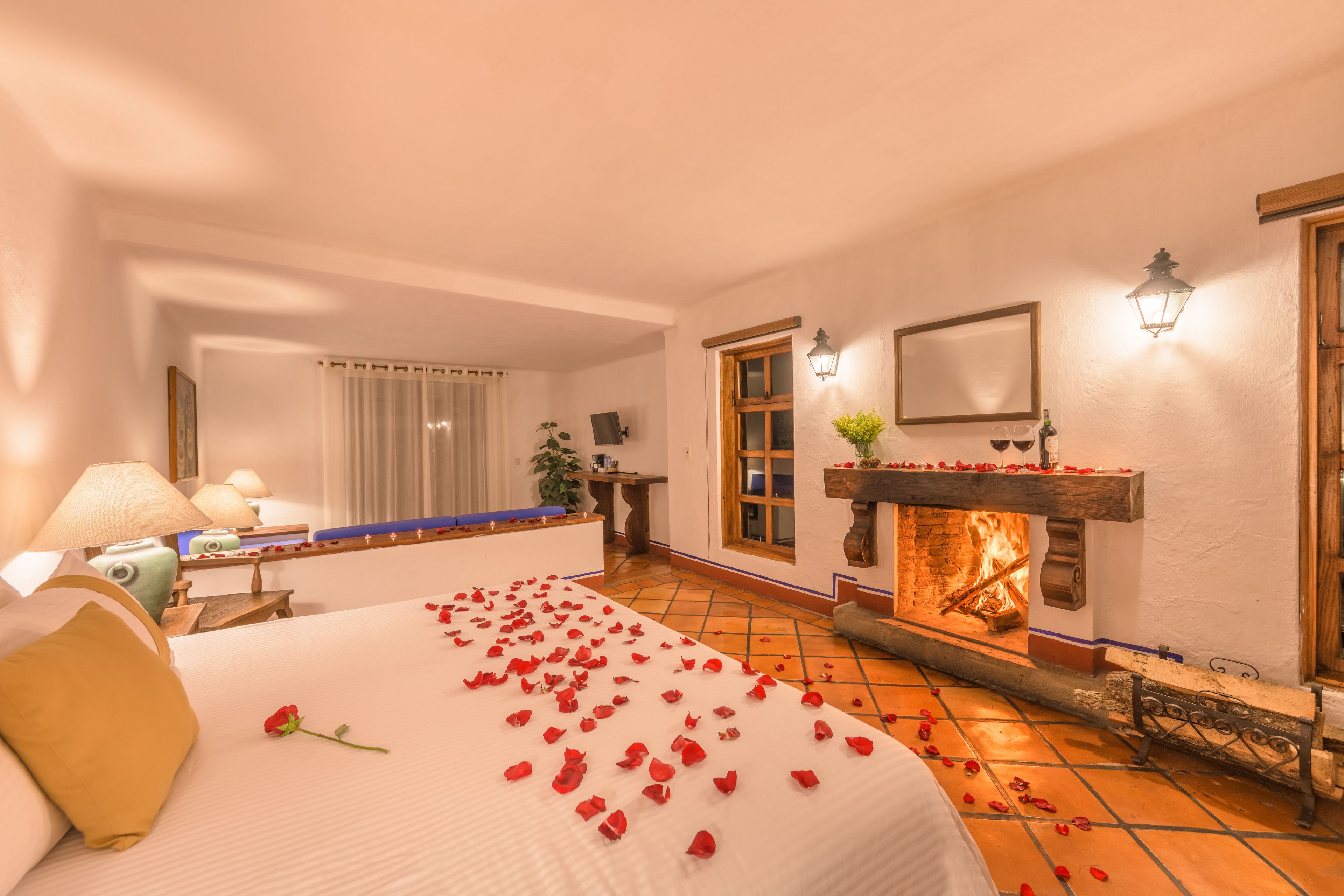 Hotellihuone, jossa on sänky, takka, oleskelualue ja suuri ikkuna.