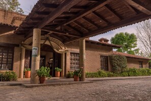 Un edificio histórico con un vestíbulo cubierto, columnas de piedra y macetas de terracota con flores.